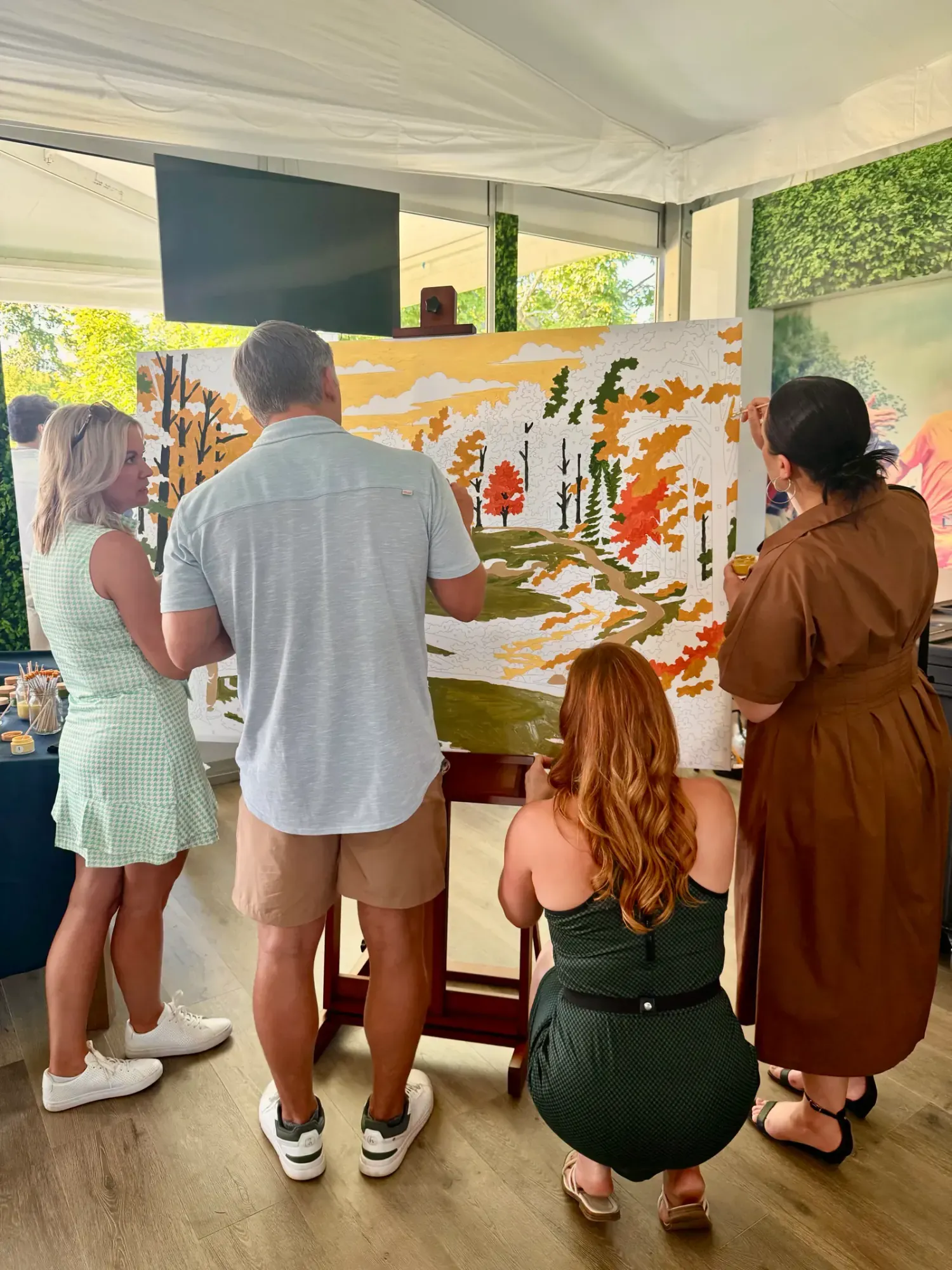 Four guests painting a golf-themed paint-by-number mural together at Muirfield Village